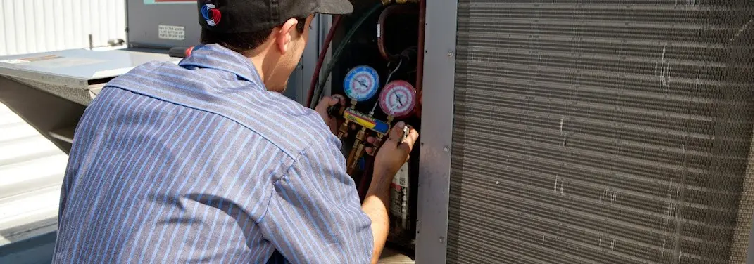 HVAC technician servicing a condenser unit in Ellicott City